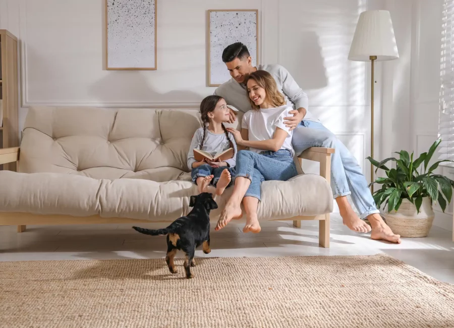 Happy family sitting on a couch at home with their dog, smiling confidently thanks to advanced Dental Technology at Gridley Dental
