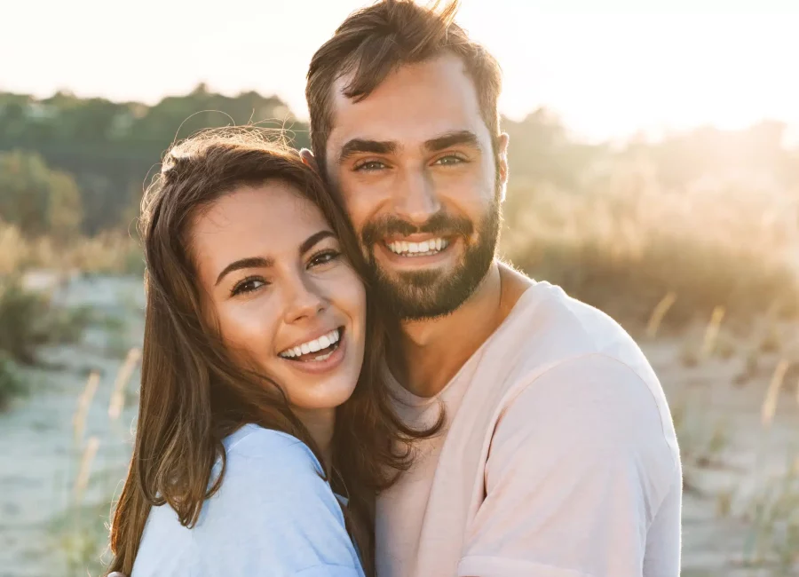 Smiling couple outdoors at sunset showing bright, healthy teeth after visiting Gridley Dental
