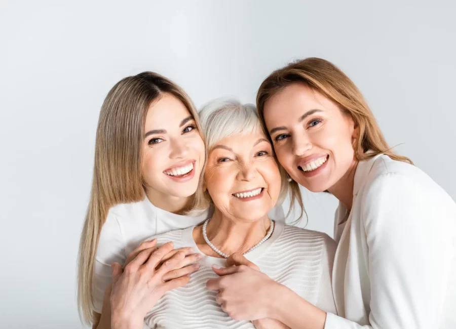 Three smiling women from different generations embracing and showing healthy teeth after Restorative Dentistry at Gridley Dental