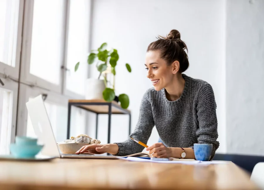 Smiling woman sitting at a desk using a laptop to review Financial Options at Gridley Dental