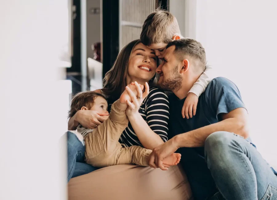 Happy family of four sitting together and smiling, showing healthy teeth after visiting Gridley Dental