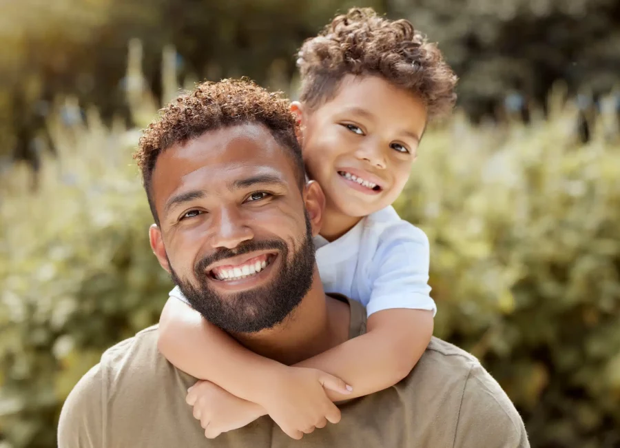 Smiling father and son outdoors showing bright, healthy teeth after Cleanings & Exams at Gridley Dental.